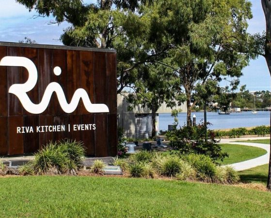 Outdoor view of Riva, surrounded by lush greenery and a path leading to a serene waterfront.