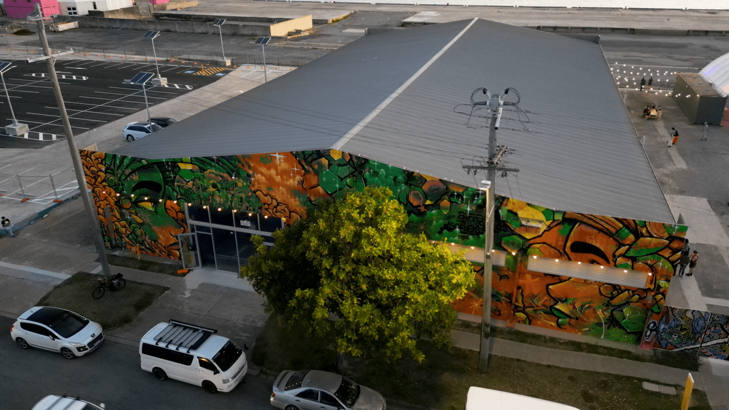 Exterior aerial view of Superordinary with a colourful graffiti facade featuring green and orange designs.
