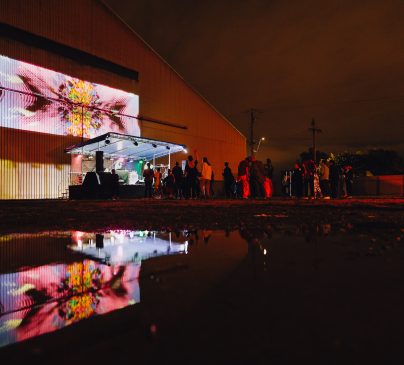 Outdoor entertainment on a stage at Superordinary, showcasing projected artwork on the exterior wall.