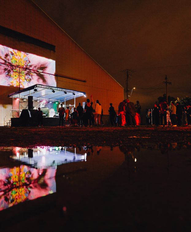 Outdoor entertainment on a stage at Superordinary, showcasing projected artwork on the exterior wall.