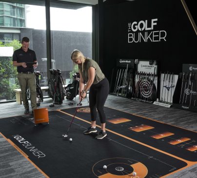 A woman practices putting at the Golf Bunker