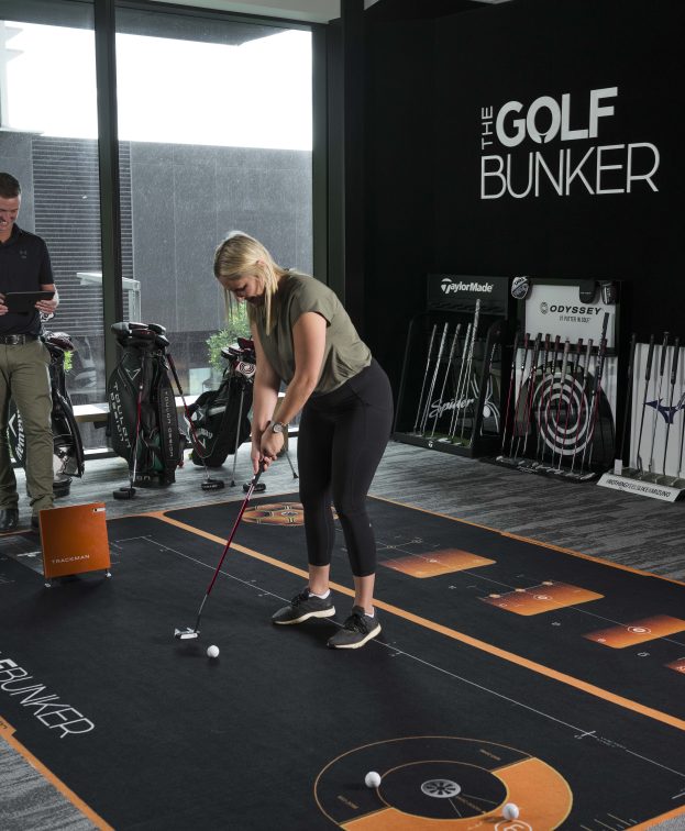 A woman practices putting at the Golf Bunker